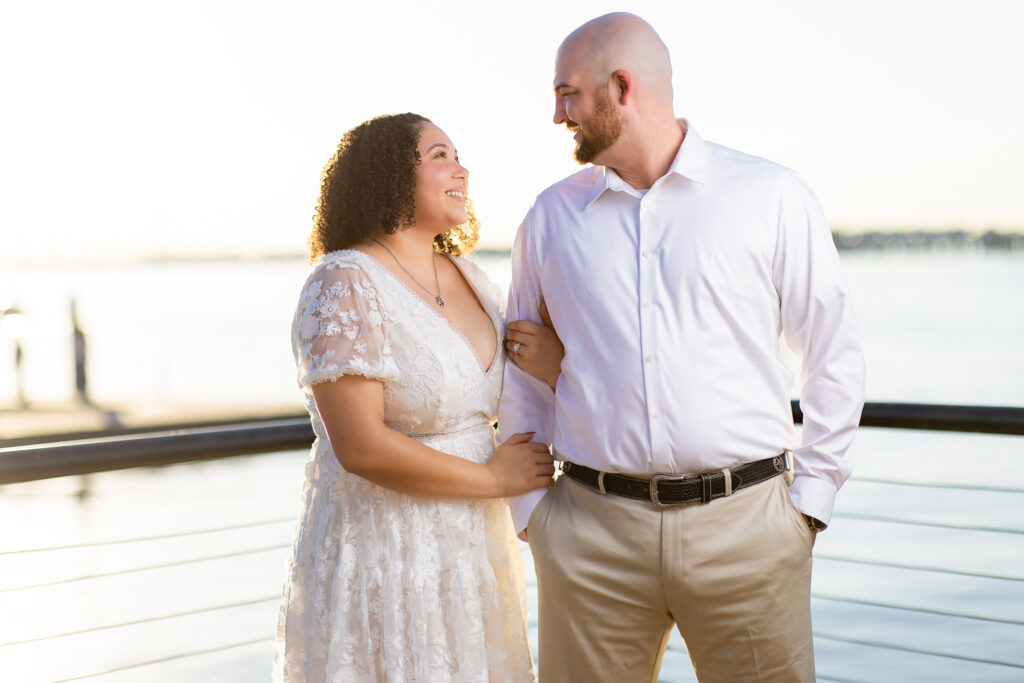 engaged man and woman wearing all white linking arms smiling at each other during Rockwall engagement session